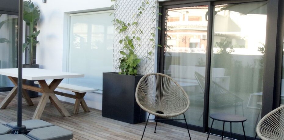 Terraza bonita y moderna con una mesa blanca con patas de madera y unas sillas de diseño. Espacio diseñado por Integra Estudio de Interiores.