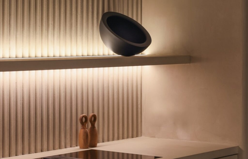 Estantería iluminada con una tira led y 3 elementos de diseño. La pared tiene textura. Integra Estudio de interiores