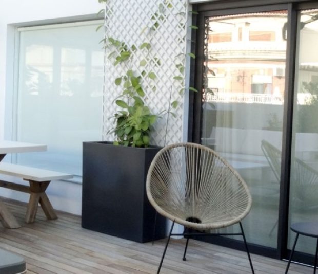 Terraza bonita y moderna con una mesa blanca con patas de madera y unas sillas de diseño. Espacio diseñado por Integra Estudio de Interiores.