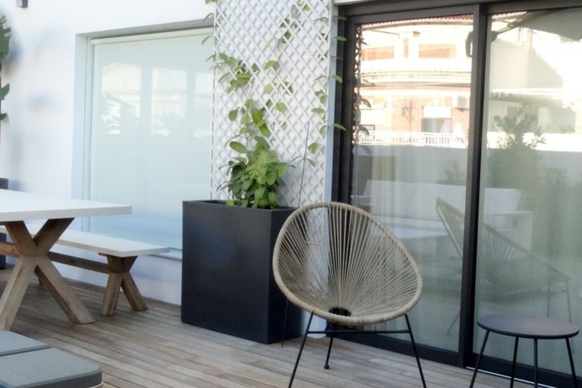 Terraza bonita y moderna con una mesa blanca con patas de madera y unas sillas de diseño. Espacio diseñado por Integra Estudio de Interiores.